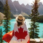 Woman wrapped in Canada flag looking at Moraine Lake